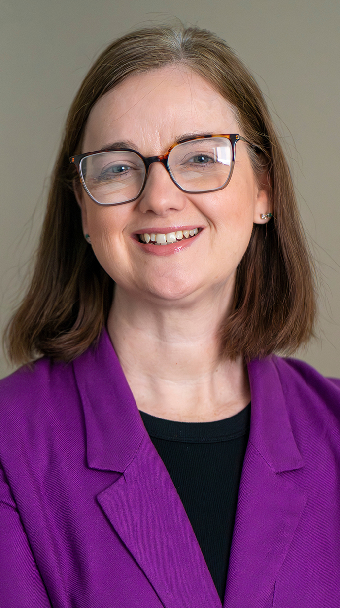 Headshot of a woman wearing a purple jacket over a black blouse.