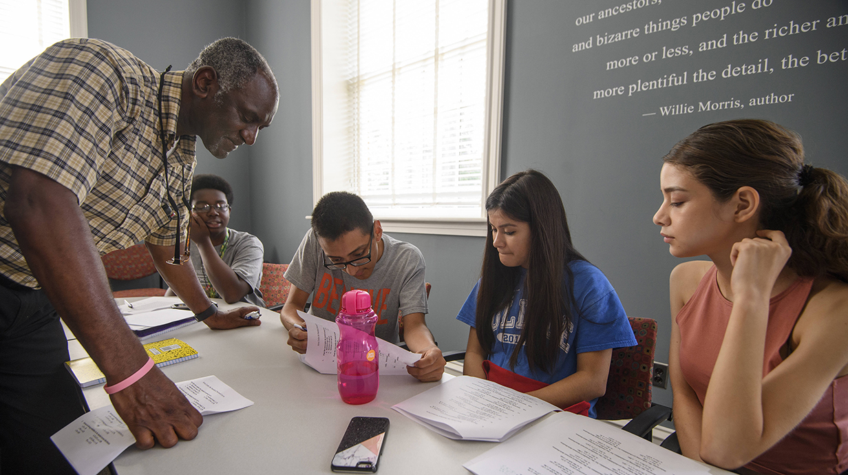 Donald Cole reads over a student's work while teaching a class. 