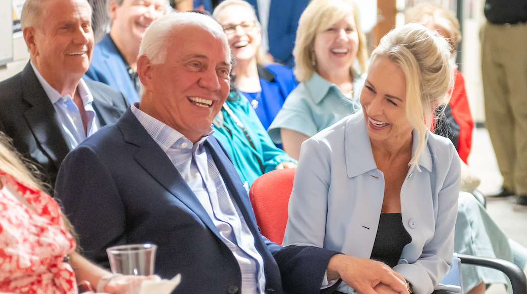 A man and a woman react to a surprise while seated in an auditorium.