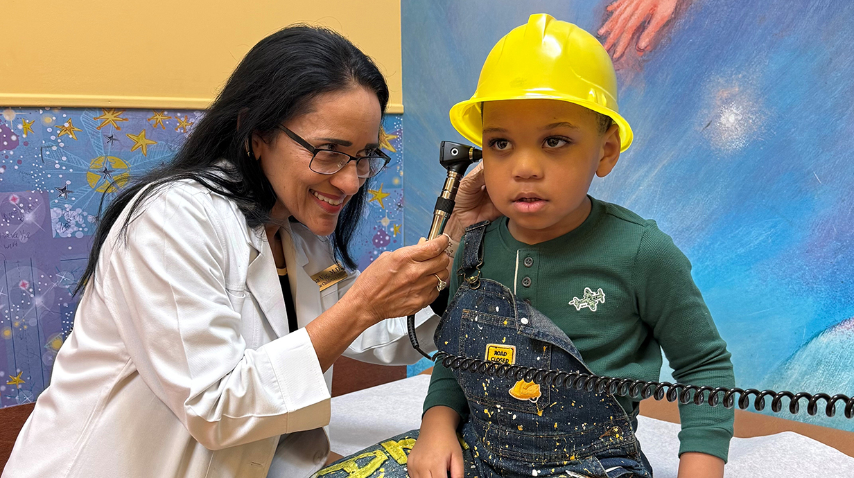 A female doctor uses an otoscope to check a young boy's ears.