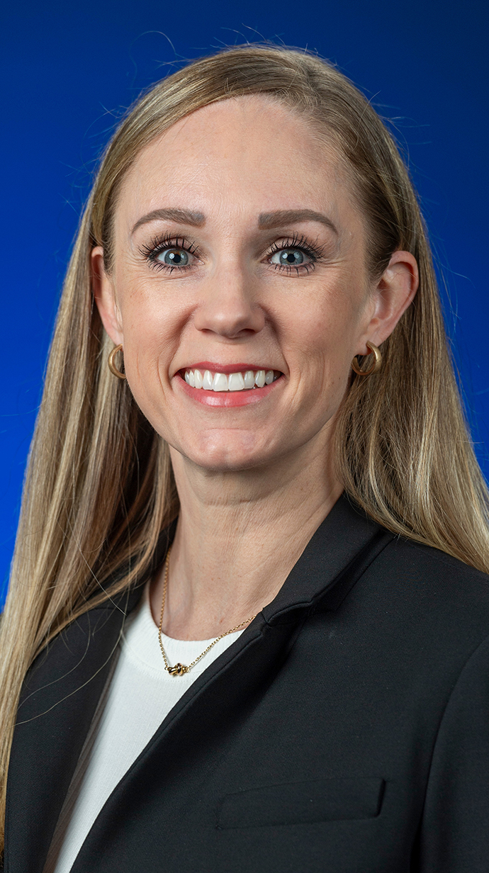 Headshot of a woman wearing a dark jacket over a white blouse.