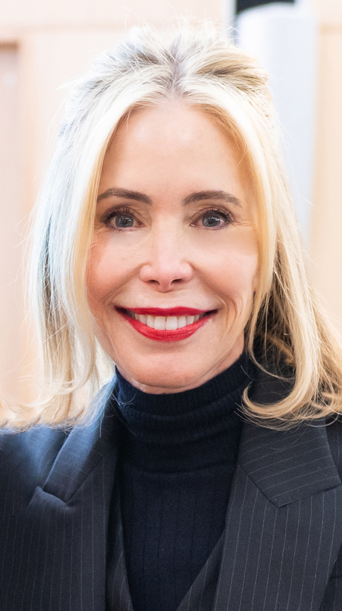 Headshot of a woman wearing a gray jacket over a black turtleneck sweater.