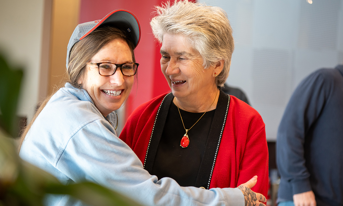 Two women share a hug and a laugh.