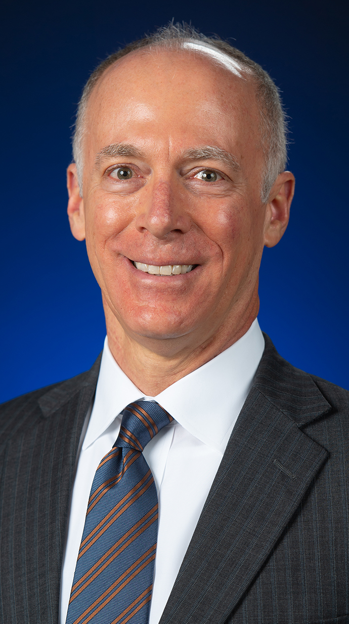 Headshot of a man wearing a gray striped suit.
