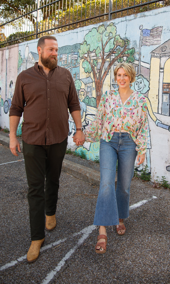 A man and woman walk past a colorful outdoor mural.