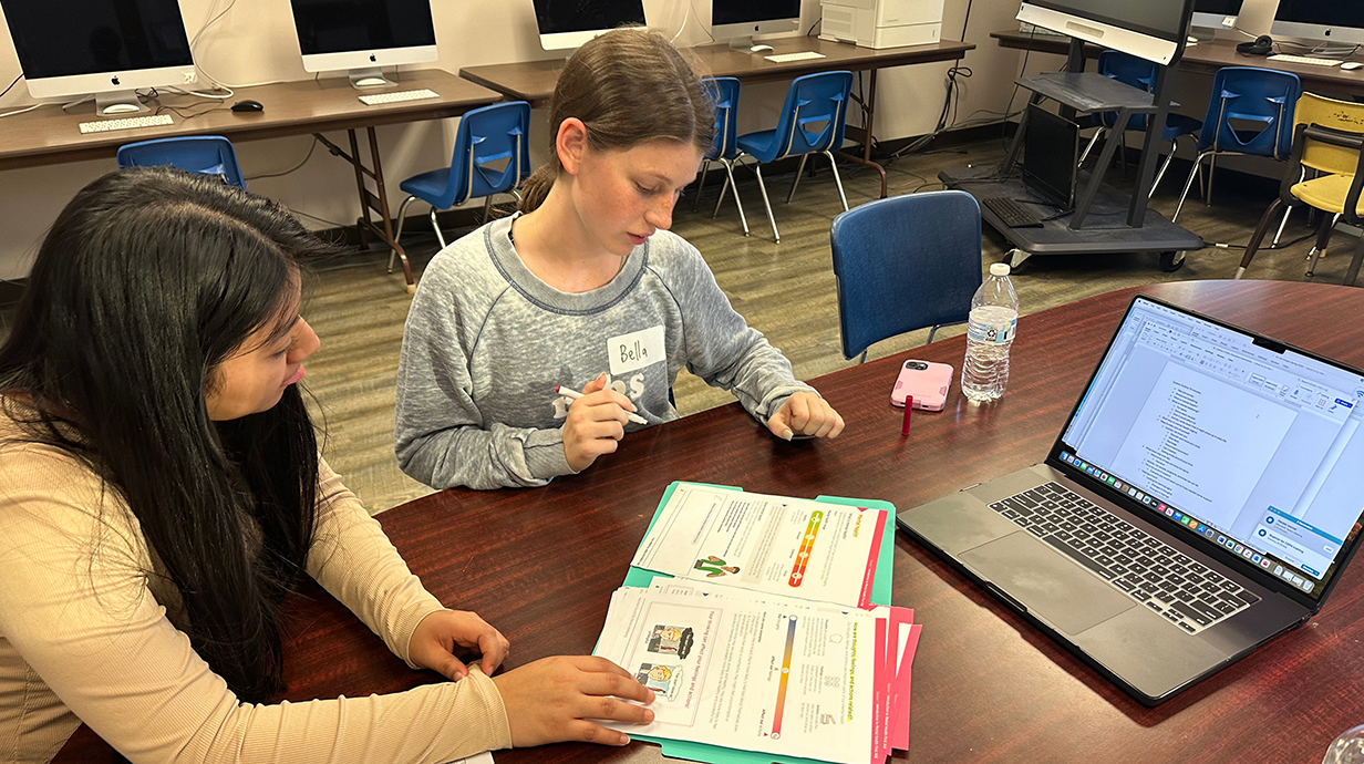 A young woman helps a girl with homework.