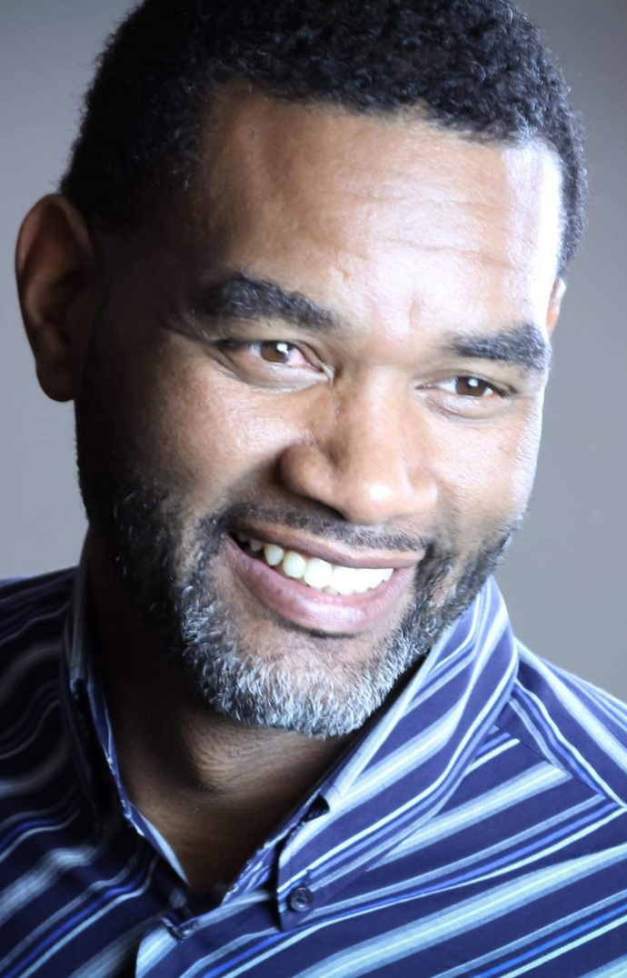 Headshot of a man wearing a blue striped shirt.
