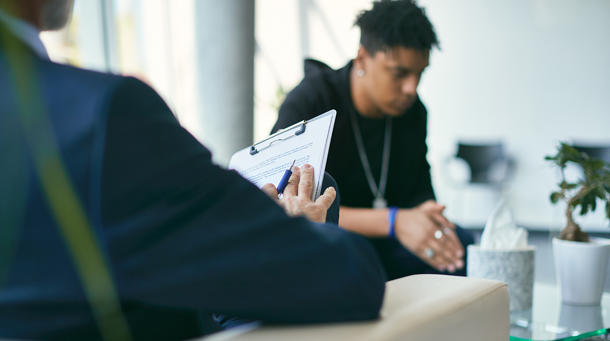 A young man dressed in black talks with a counselor.
