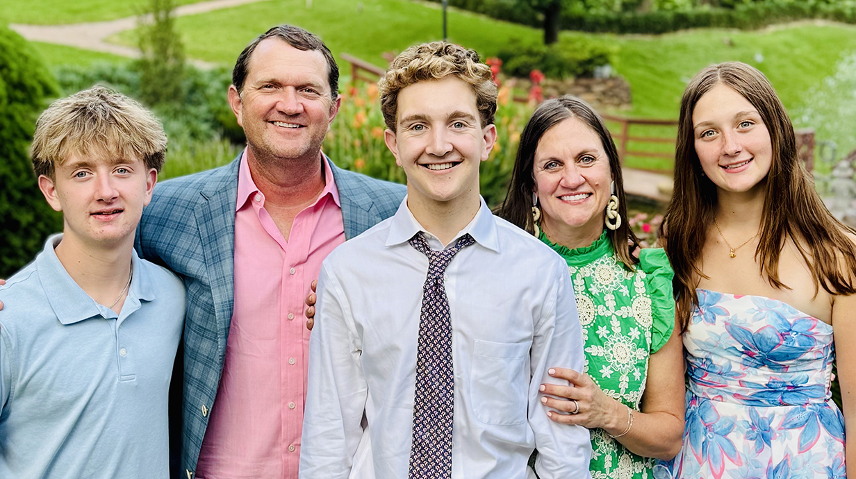 A man and woman take a family photo with two sons and a daughter.
