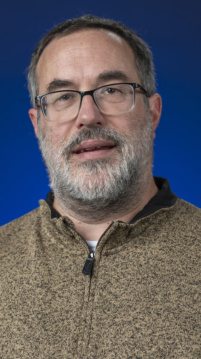 Headshot of a man wearing a brown zippered shirt.