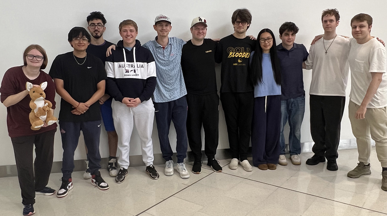 A group of young people, one holding a stuffed kangaroo, post for a group photo.