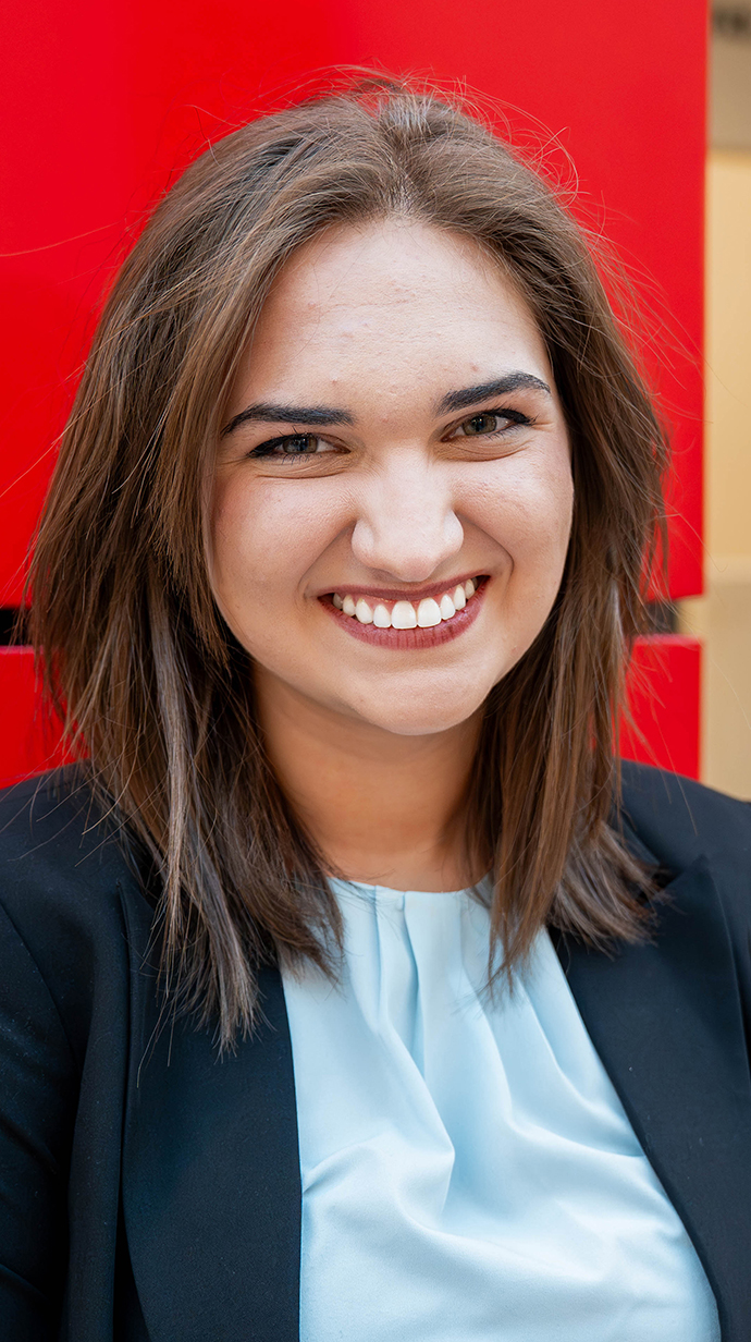 Headshot of a young woman wearing a dark blue jacket over a light blue blouse.