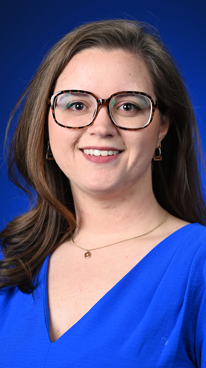 Headshot of a woman wearing glasses and a royal blue blouse.