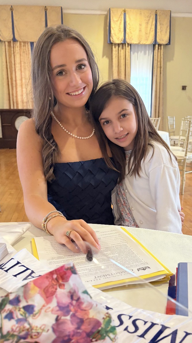 A young woman and a girl sit at a table in a formal dining room.