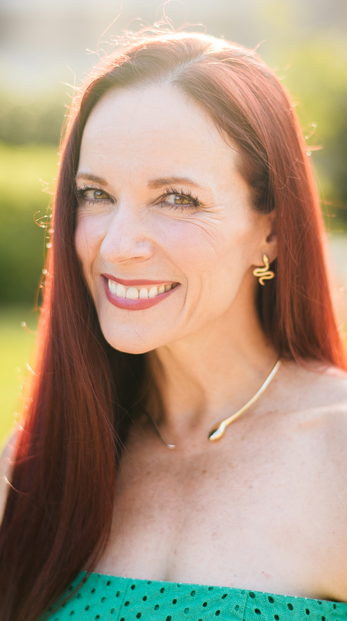 Headshot of a woman wearing a low-cut green dress.