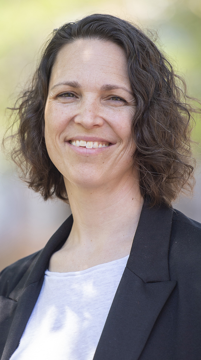Headshot of a woman wearing a dark jacket over a white blouse.
