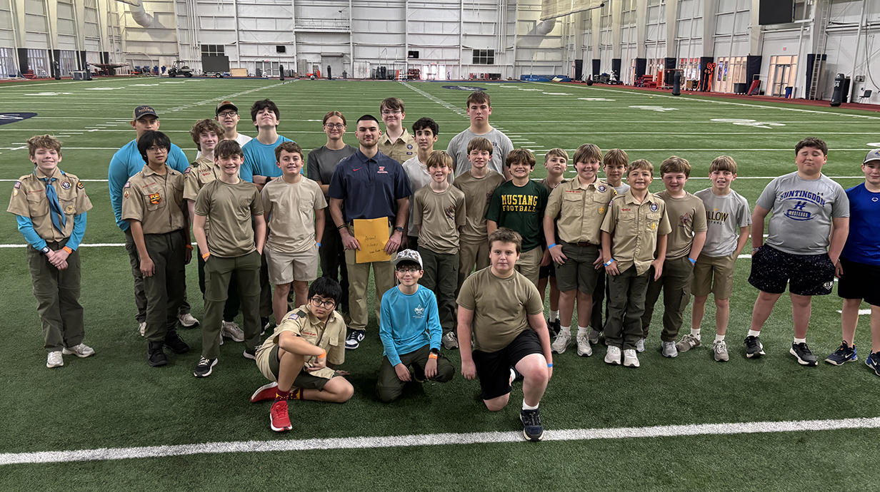 A large group of young people assemble on an indoor football field.