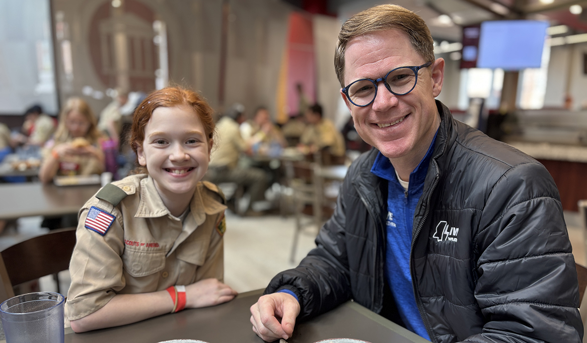 A man and a young woman share lunch in a cefeteria.
