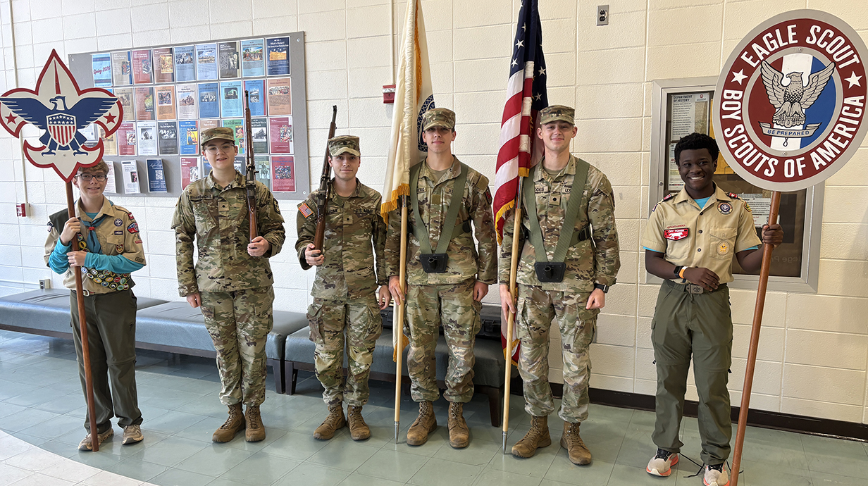 ROTC cadets dressed in fatigues prepare to present the colors in a flag ceremony.