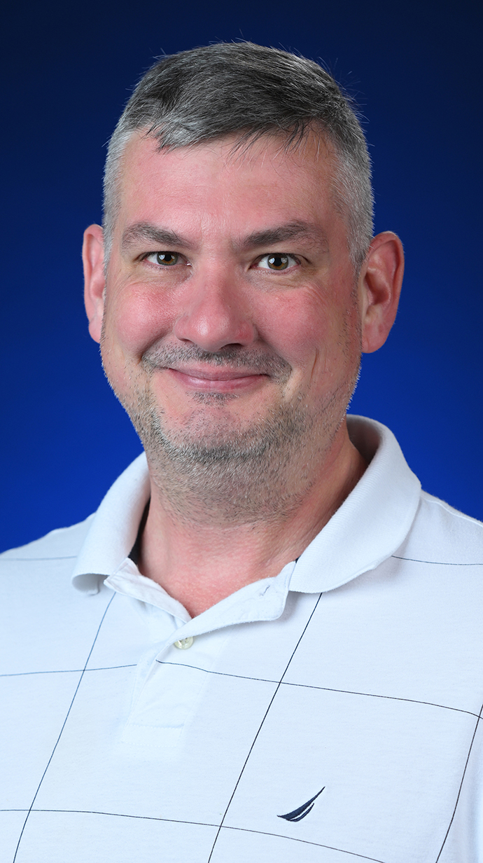 Headshot of a man wearing a white polo shirt.