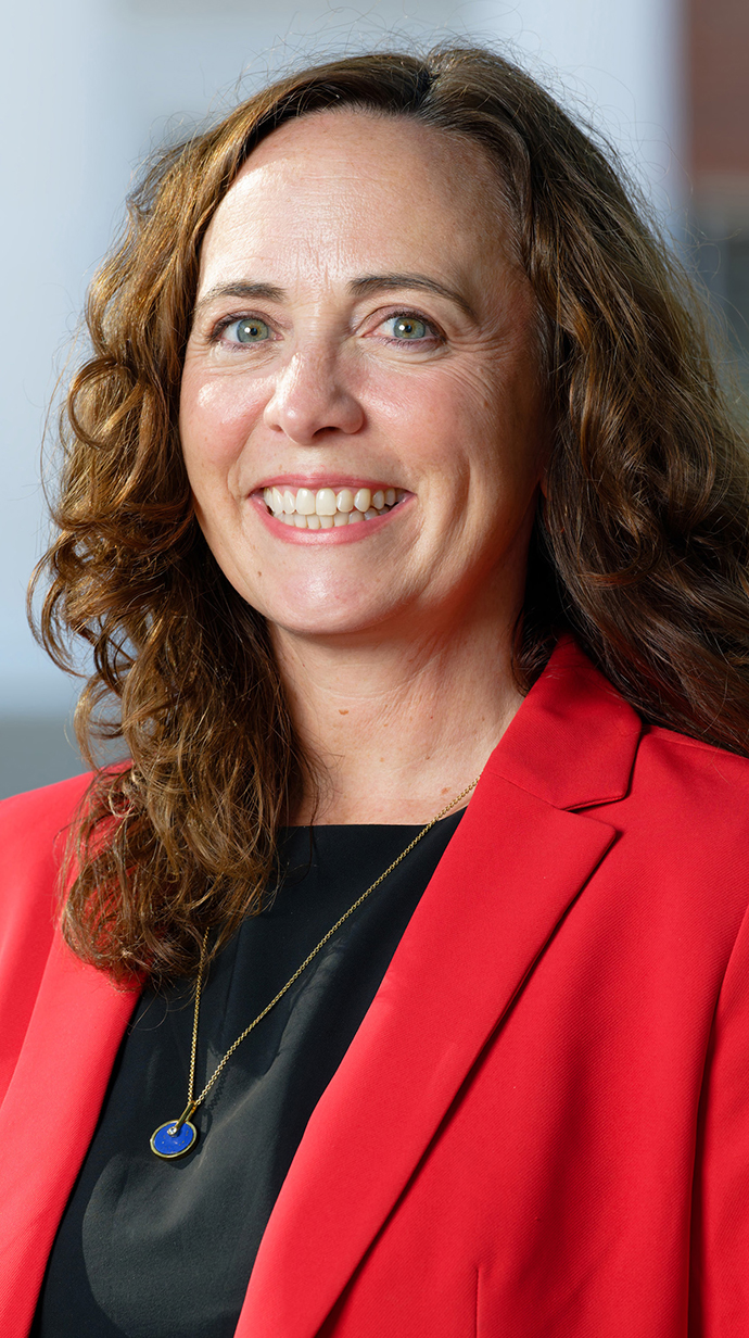 Headshot of a woman wearing a red jacket over a black blouse.