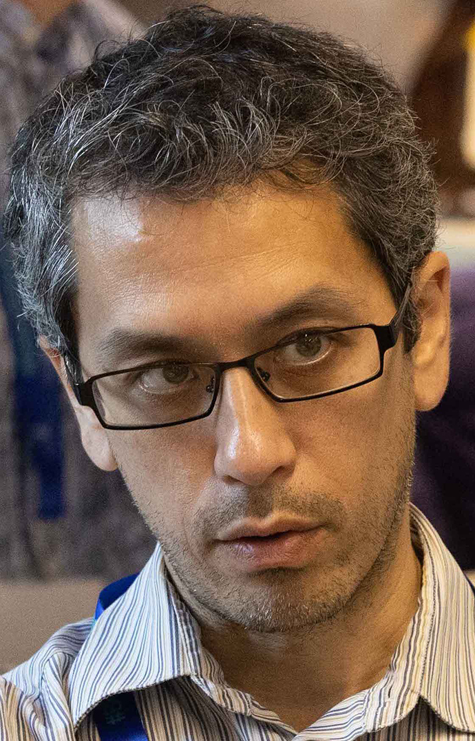 Headshot of a man wearing glasses and a striped dress shirt.
