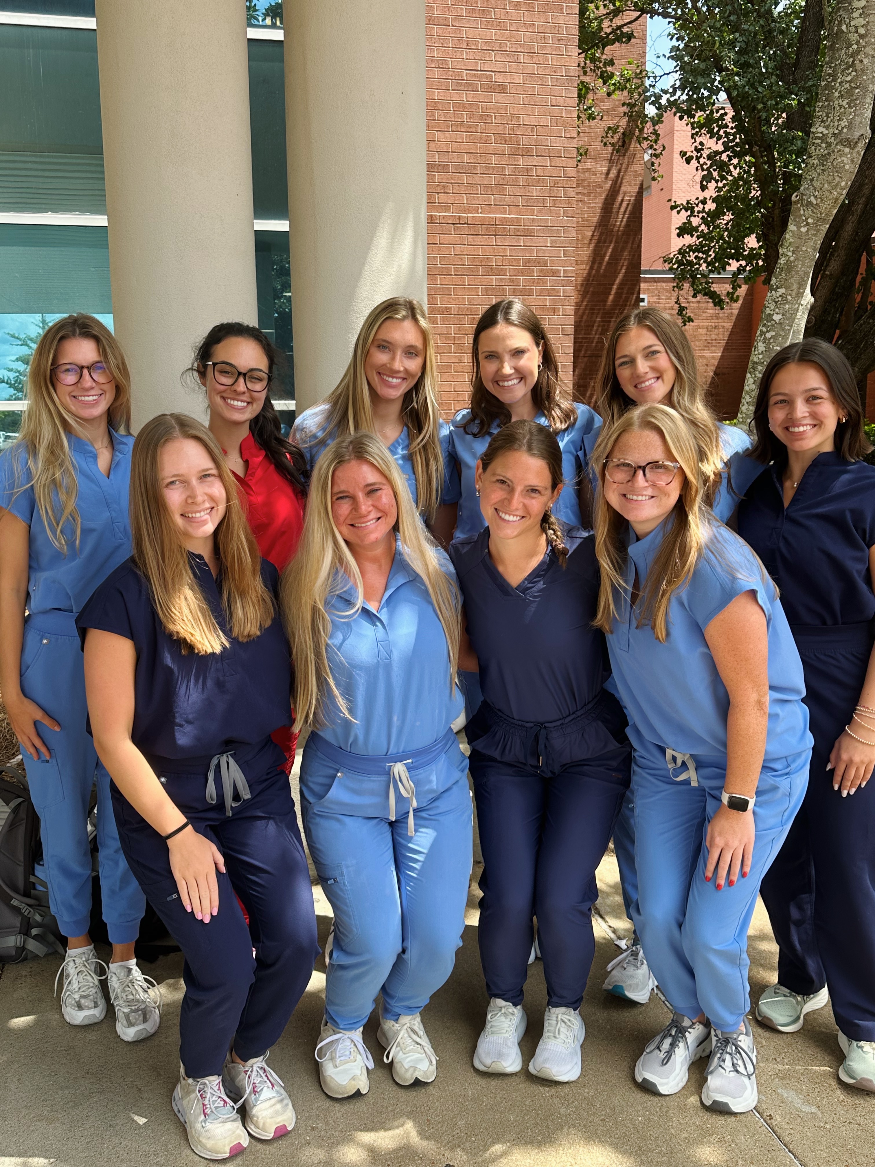 Ten friends in blue scrubs pose for a photo