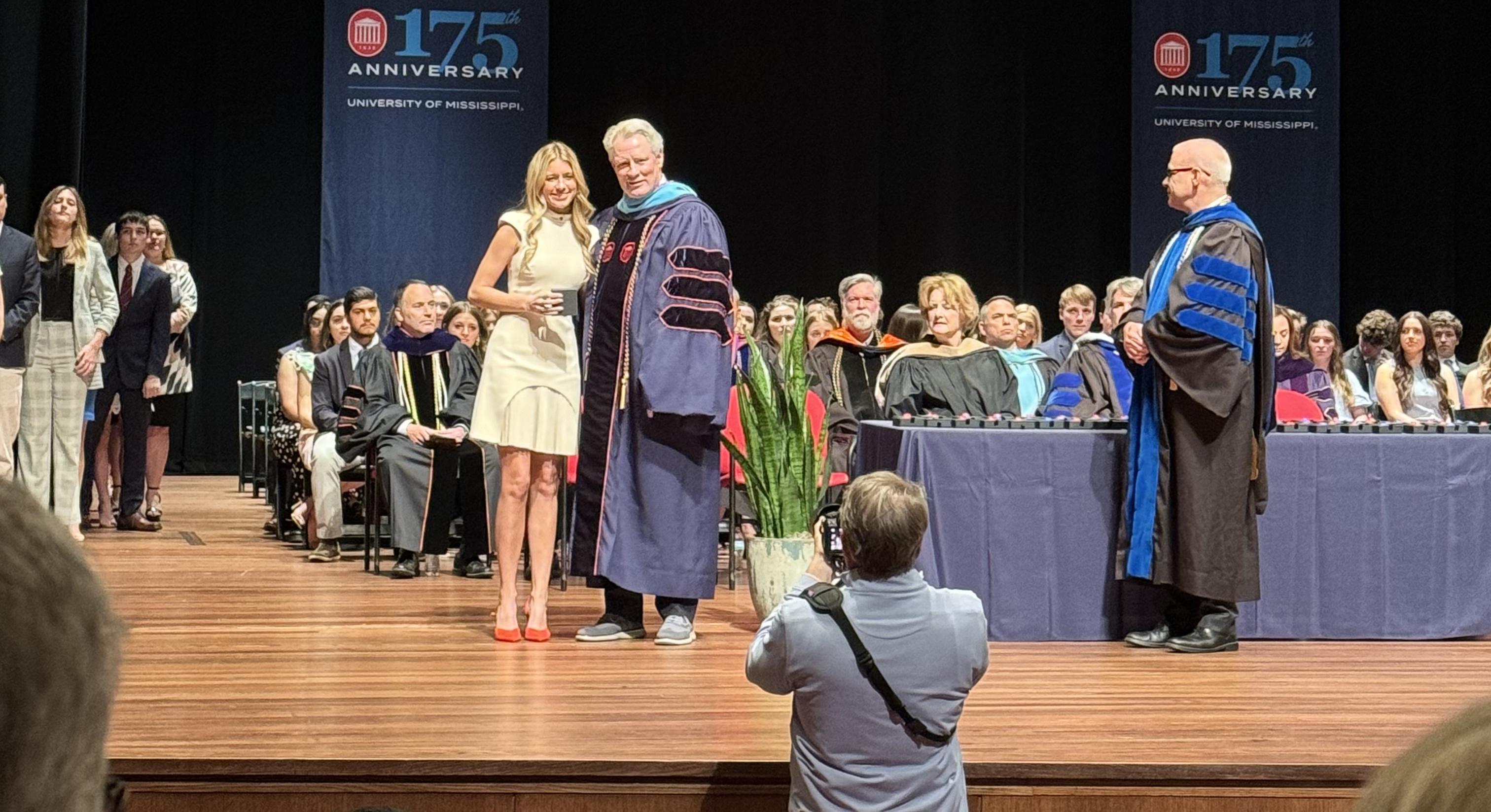 Collins stands on a stage with Chancellor Glenn Boyce.