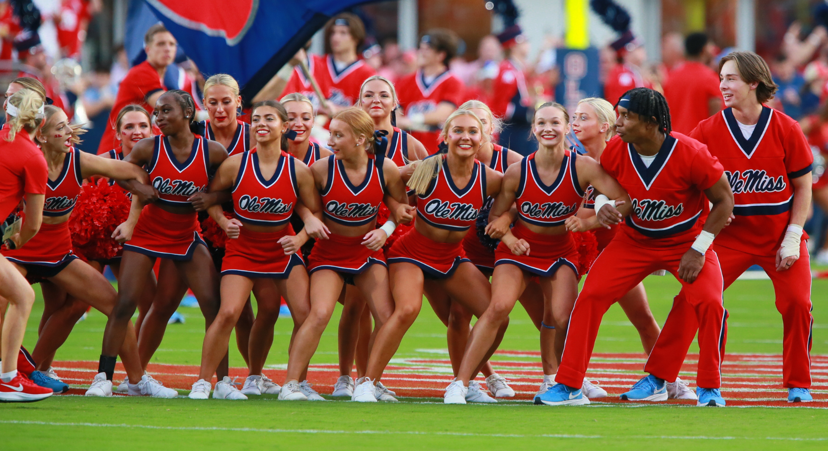 Image of cheerleaders locking arms on a football field.