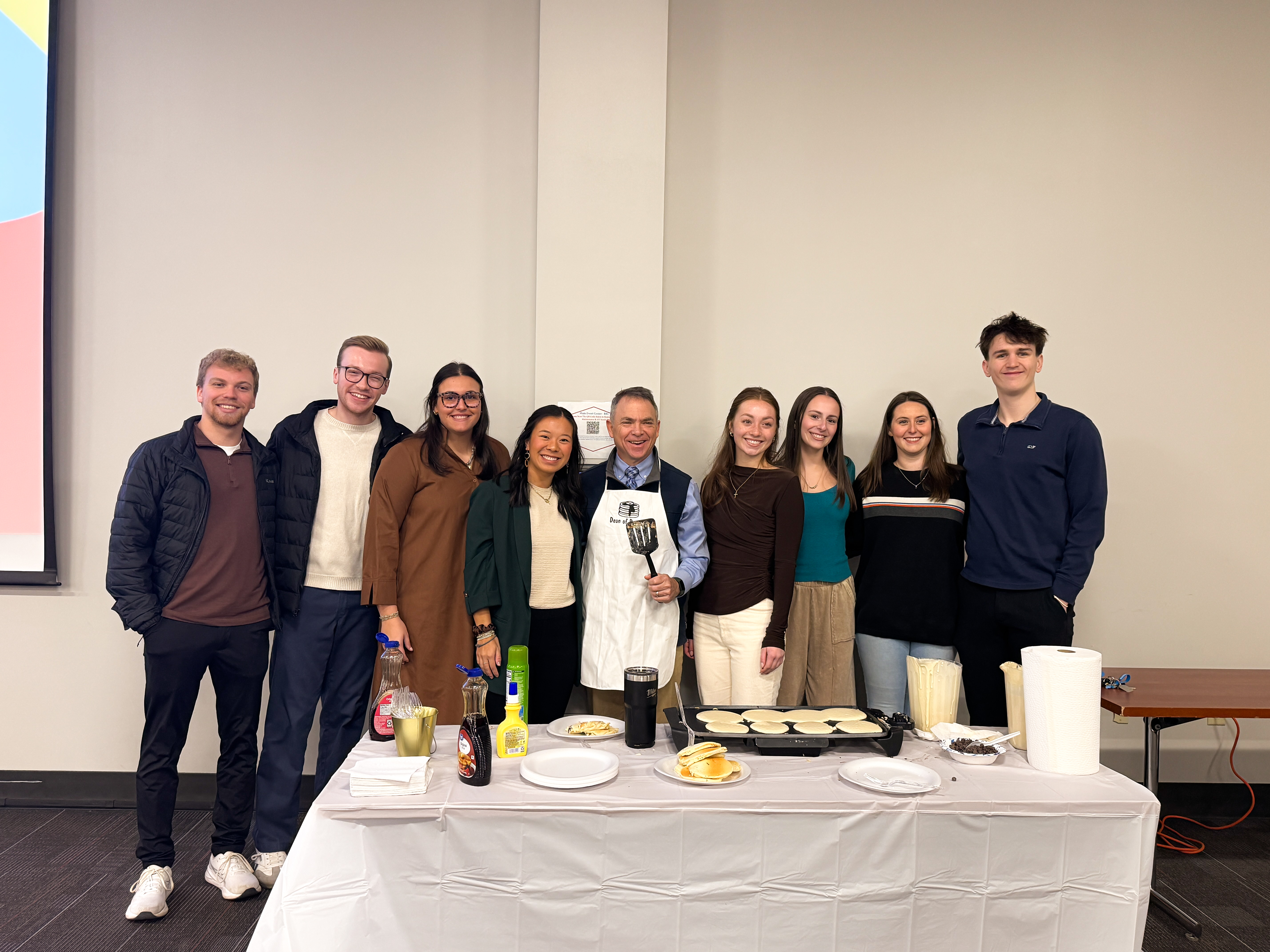 Image of eight students and Dean Rock smiling for a picture