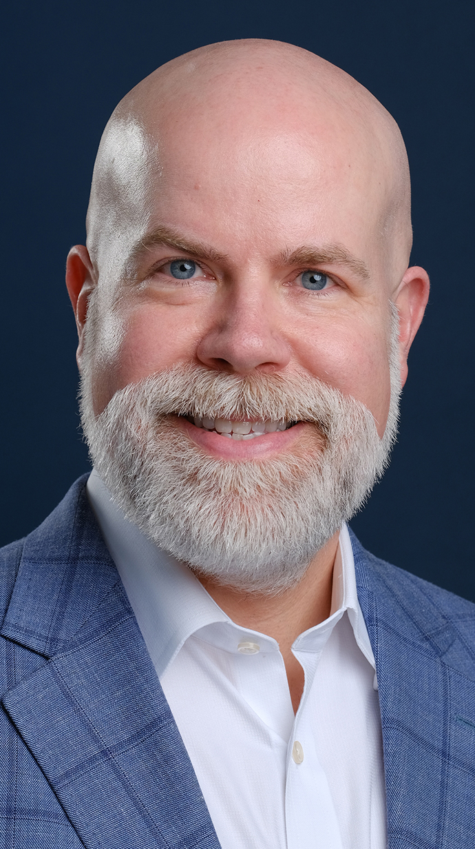 Headshot of a man wearing a blue jacket over a white shirt.