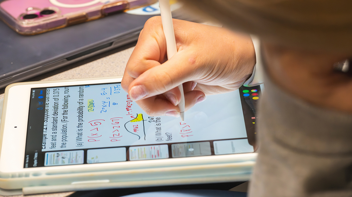 A person works a math problem on an electronic tablet.