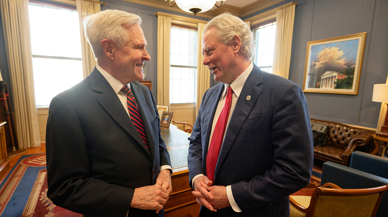 Two men chat in an ornate office.