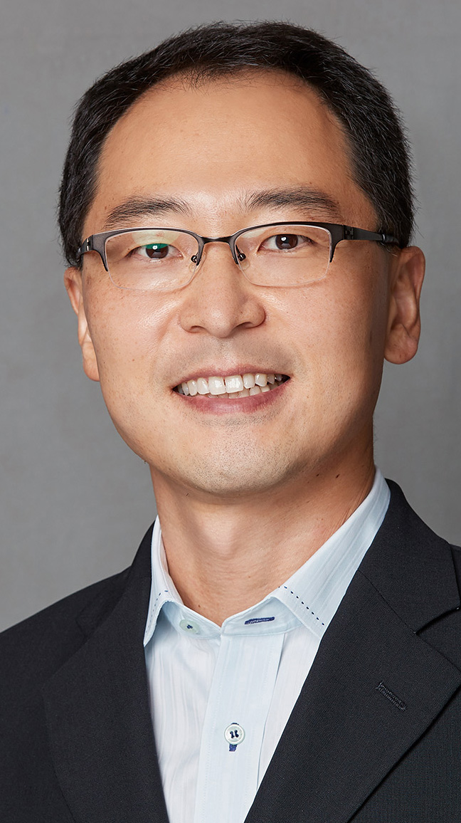 Headshot of a man wearing a dark jacket over a light blue shirt.