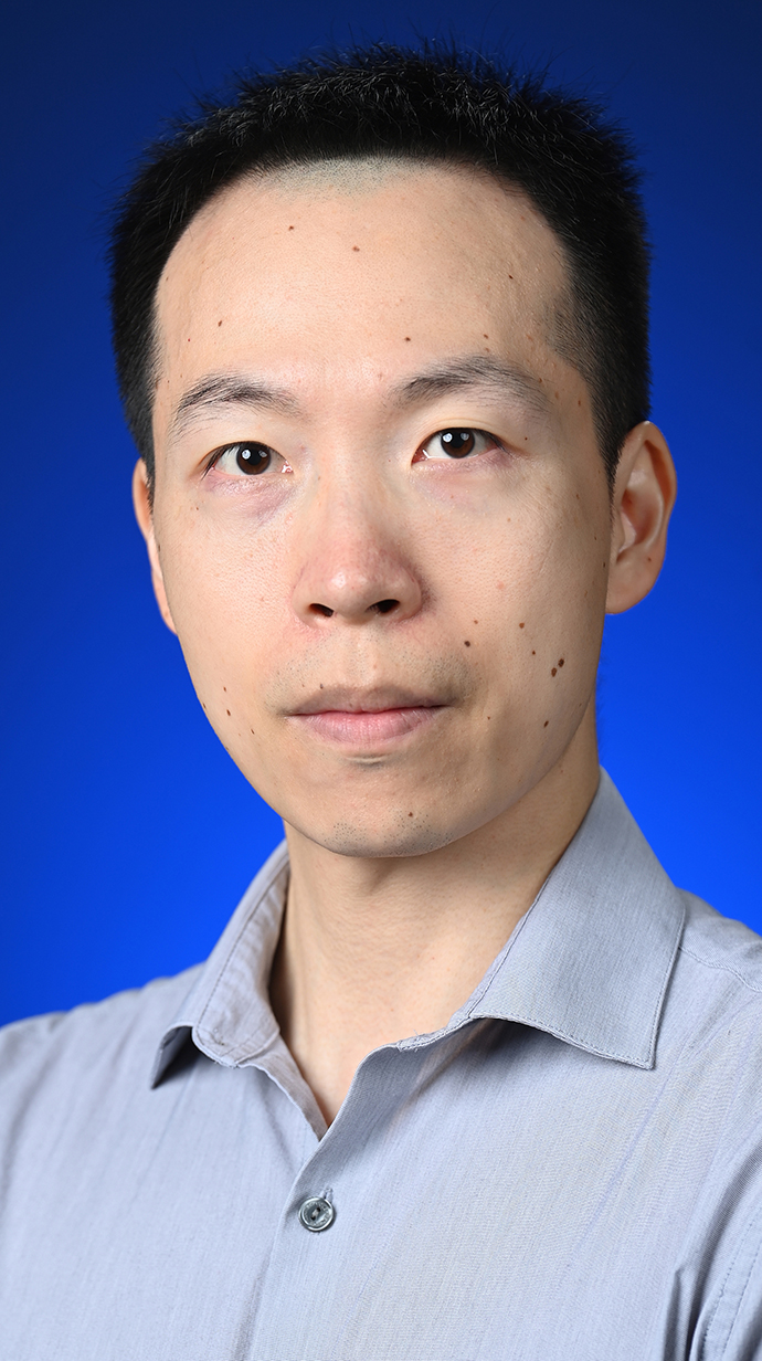 Headshot of a man wearing a gray button-up shirt.