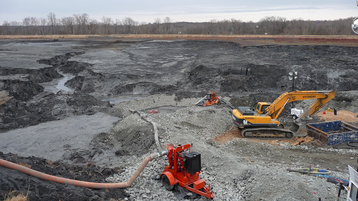 Heavy equipment sits on bare earth in an industrial site.