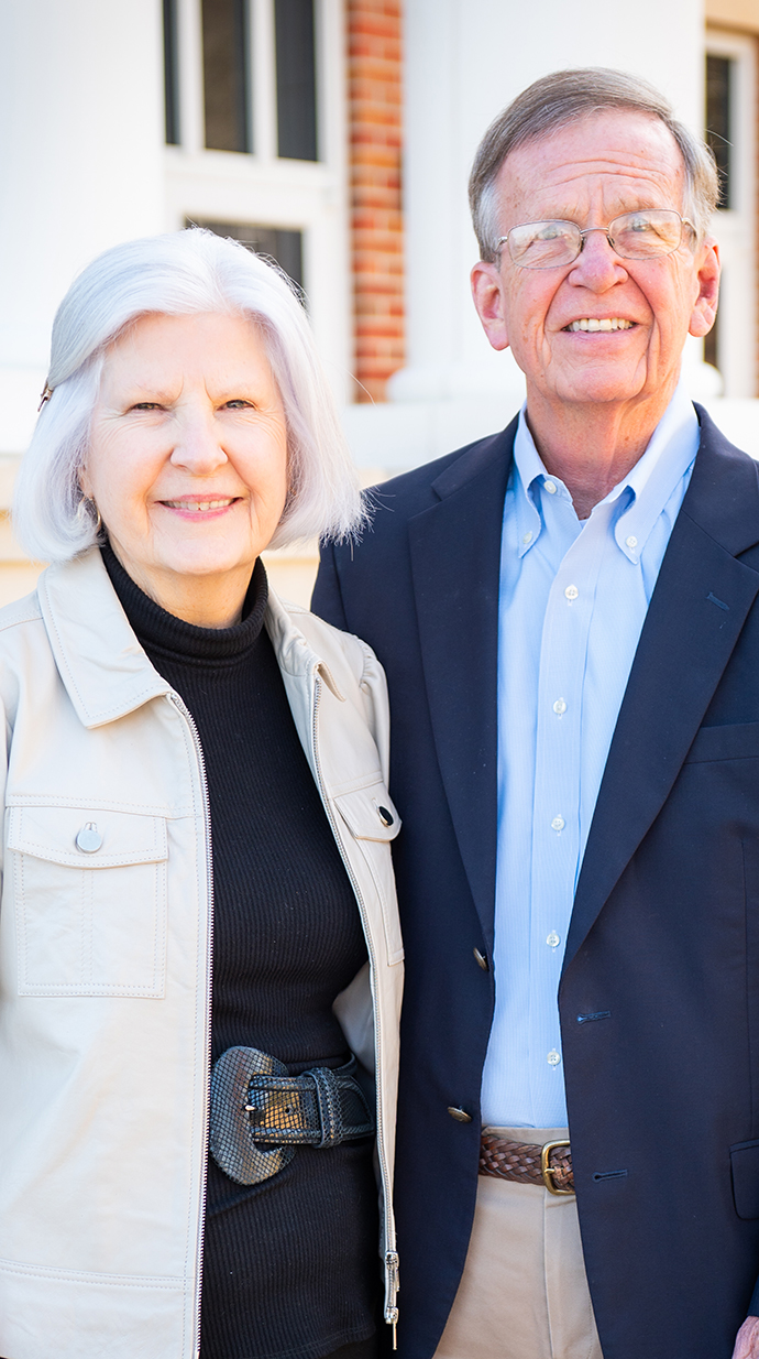 A woman and a man stand outside a brick building.