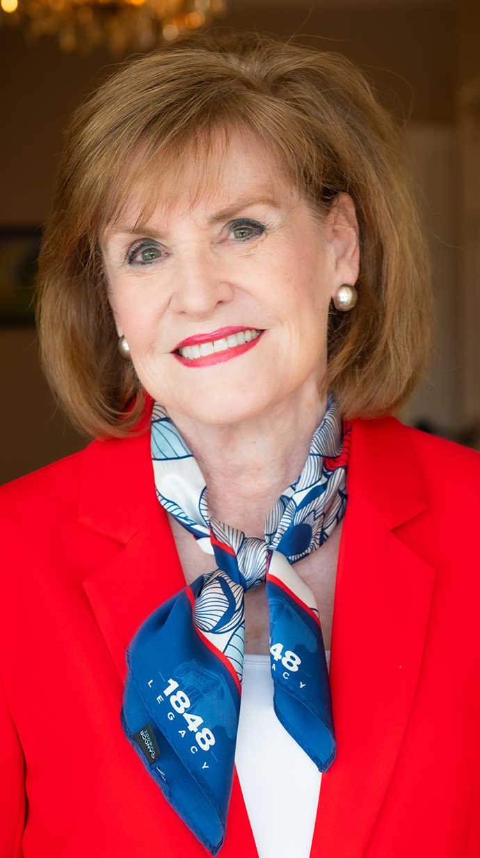 Portrait of a woman wearing a red jacket with a blue scarf.