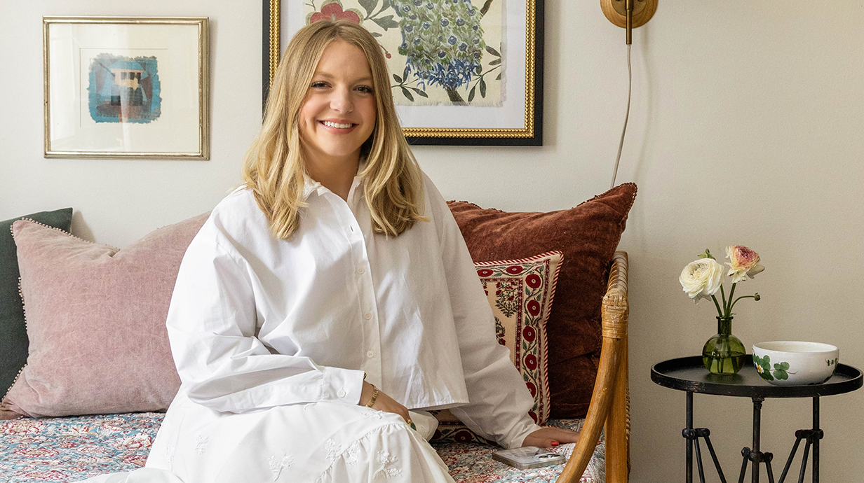 A woman wearing a white dress sits on a sofa.