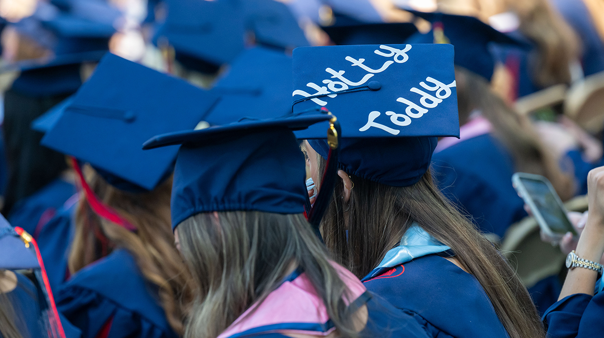 A young woman wears a graduation cap with 'Ole Miss' painted on the top.