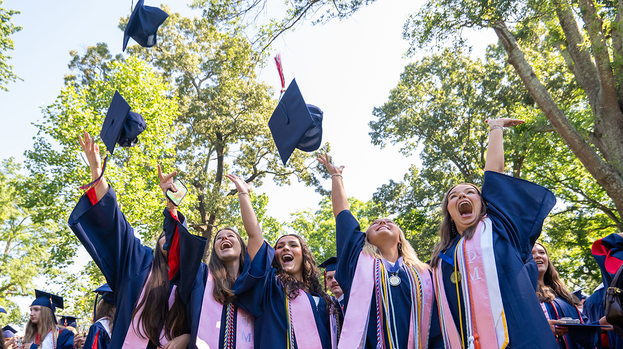 A group of young people toss their caps into the air at a graduation ceremony.