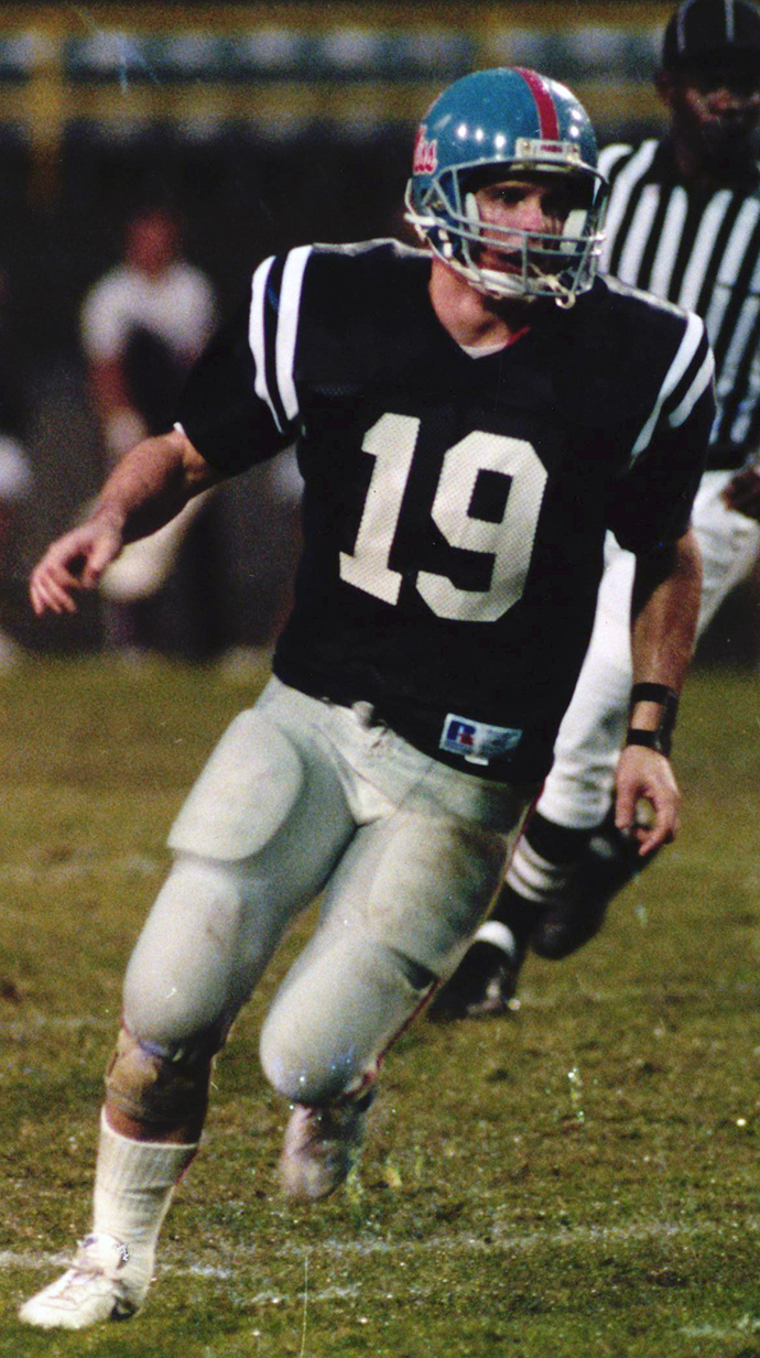 A football player stands on the field in a stadium.