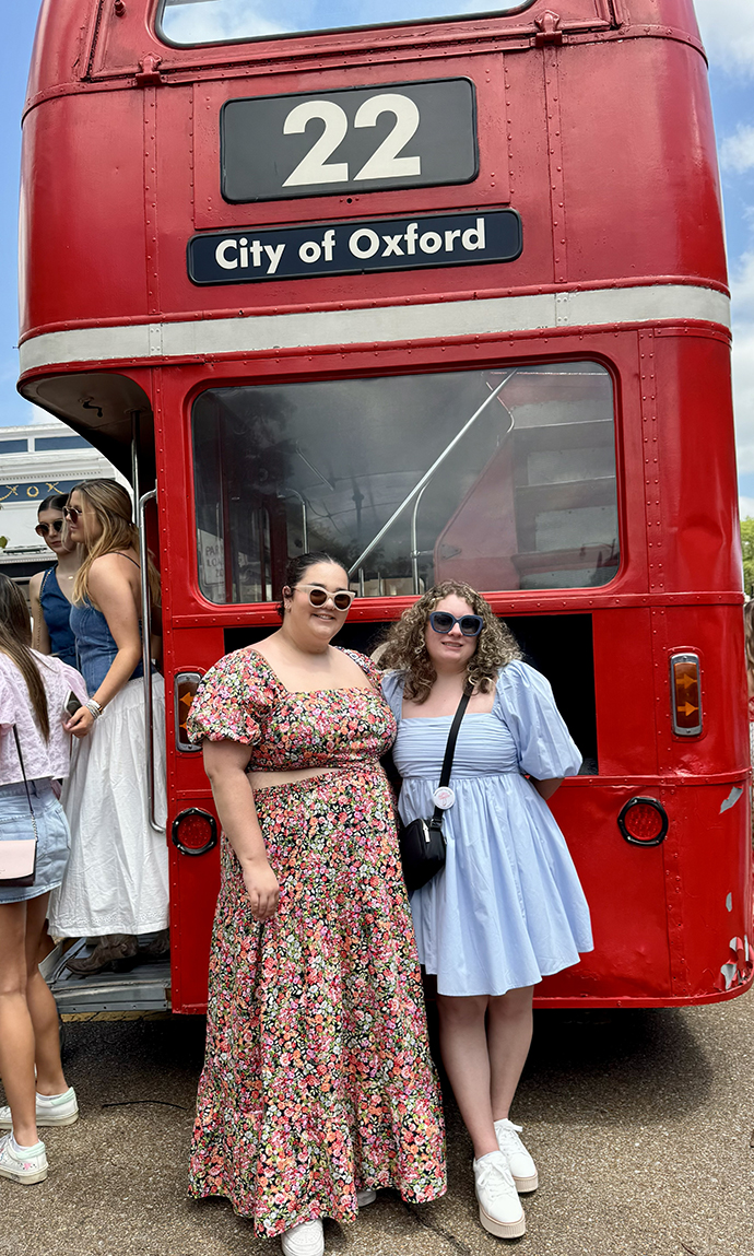 Nilmary Padilla and a friend stand in front of a red Double Decker bus.