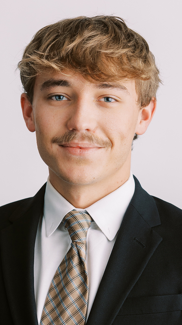 Headshot of a young man wearing a dark suit.