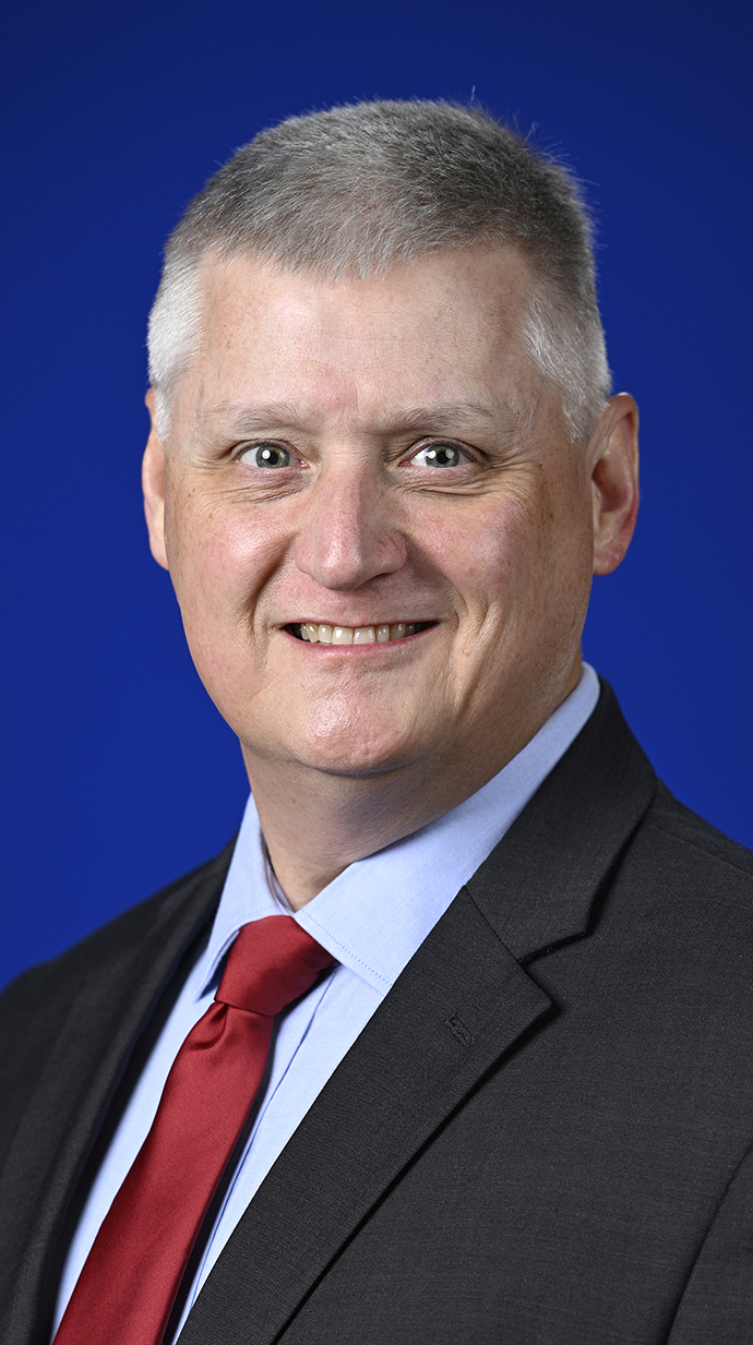 Headshot of a man wearing a dark blue suit with a red tie.