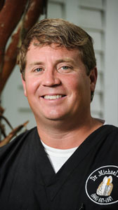 Headshot of a man wearing black medical scrubs.