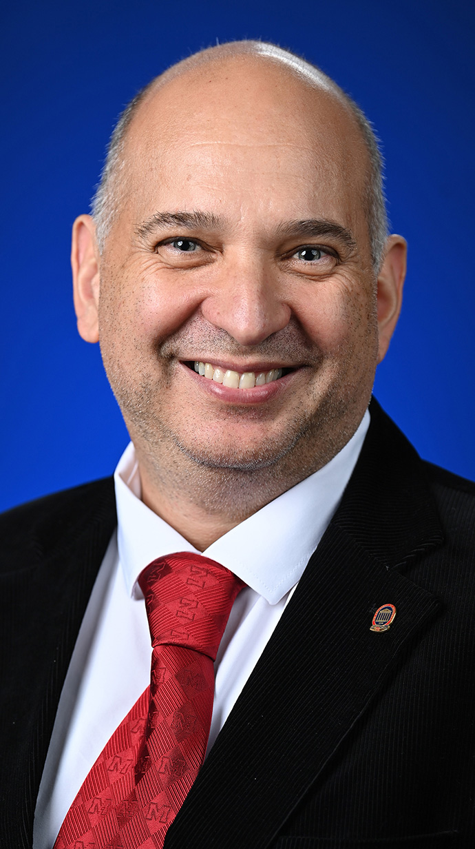 Headshot of a man wearing a dark suit with a red tie.