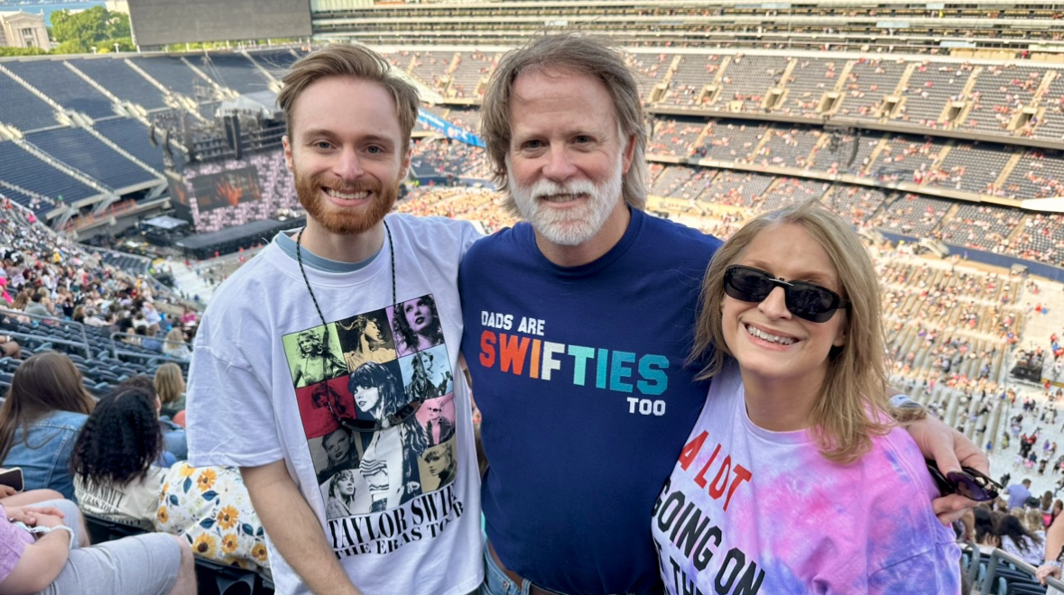 A young man, an older man and a woman stand in a stadium before a concert.