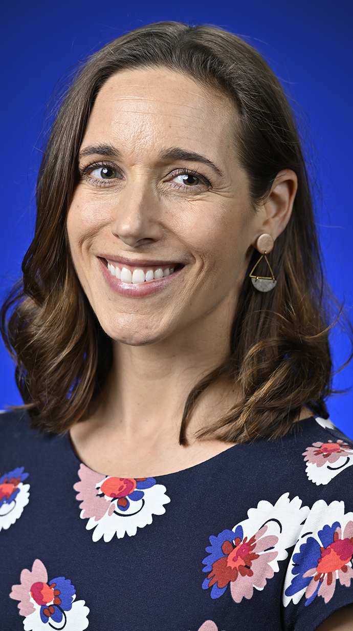 A woman wears a black blouse printed with colorful flowers.