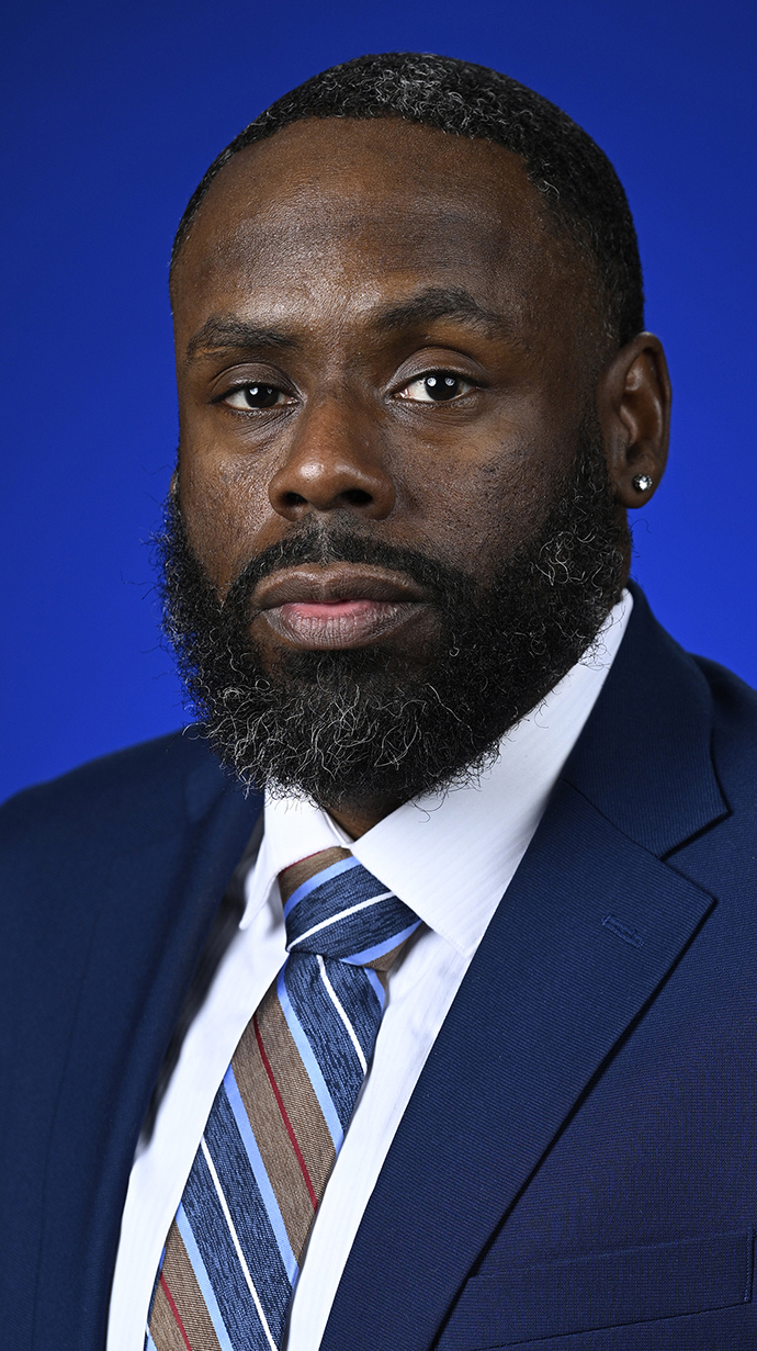 Headshot of a man wearing a dark blue suit with a striped tie.